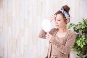 おでこを鏡で見る女性