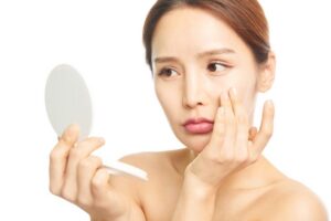 鏡で顔を見つめる女性